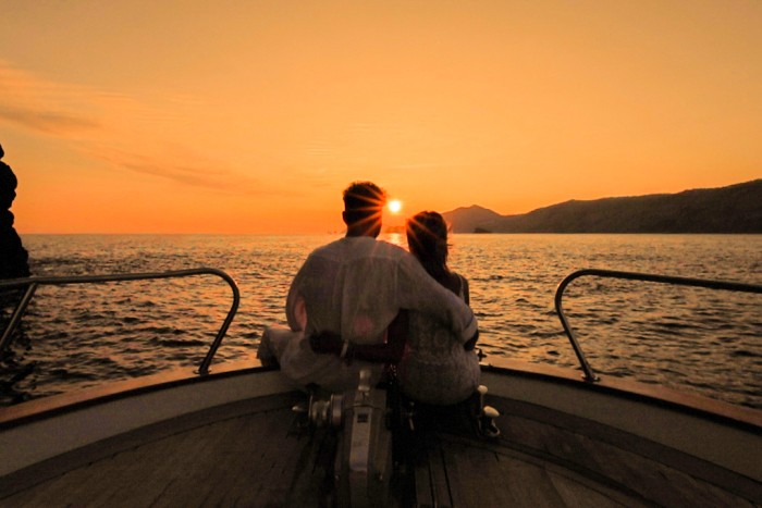 Two persons on the bow of a bow looking at sunset