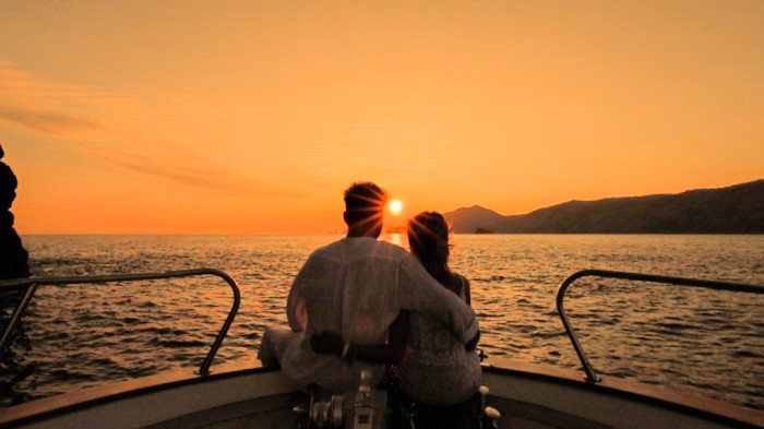 Two people on the bow of the boat looking at sunset