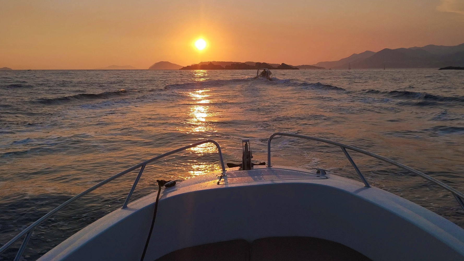 Two people on the bow of the boat looking at sunset